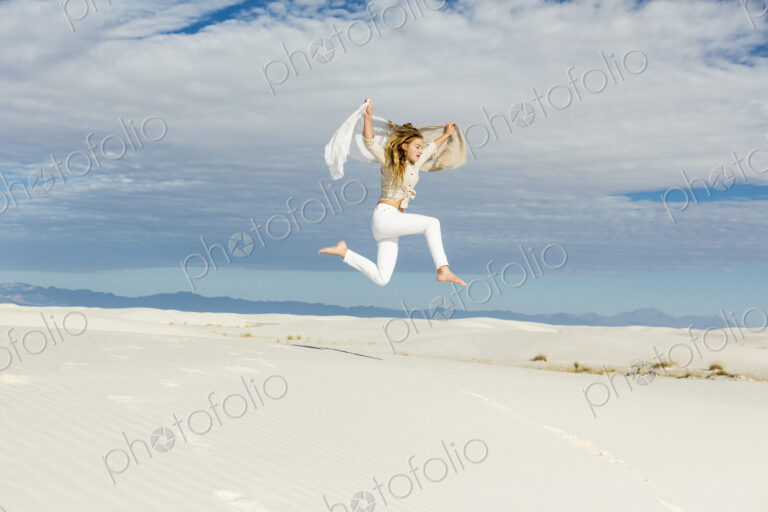 13 year old girl dancing and leaping n mid air in the open space on white sand dunes