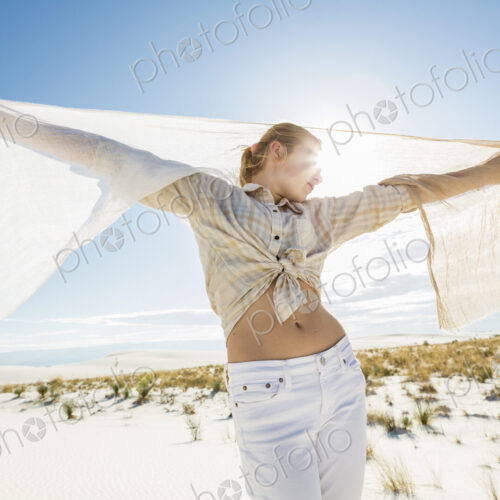13 year old girl dancing with a shawl in the open space of white sand dunes.