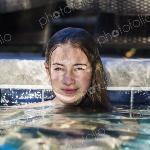13 year old girl in pool with reflections playing on her face 13 year old girl in pool with reflections playing on her face