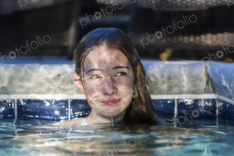 13 year old girl in pool with reflections playing on her face