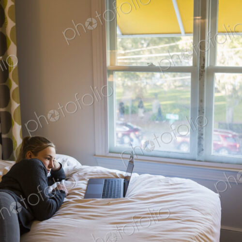 13 year old girl lying on bed watching her laptop 13 year old girl lying on bed watching her laptop