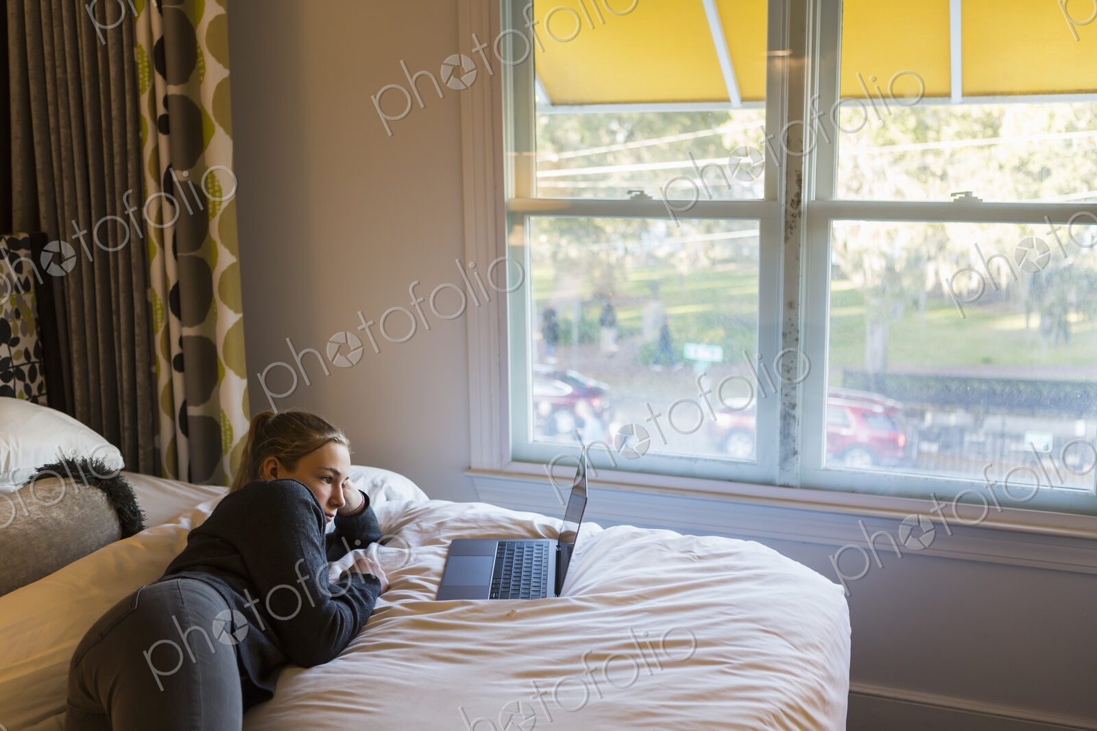 13 year old girl lying on bed watching her laptop