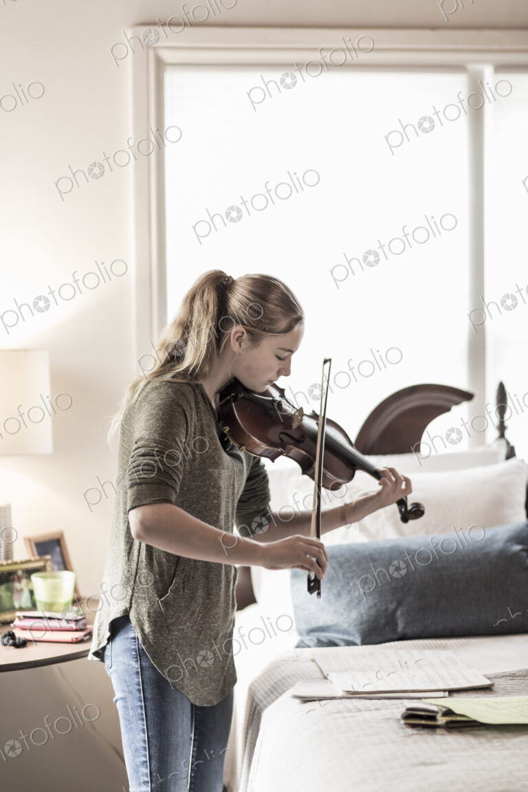 13 year old girl playing violin in bedroom