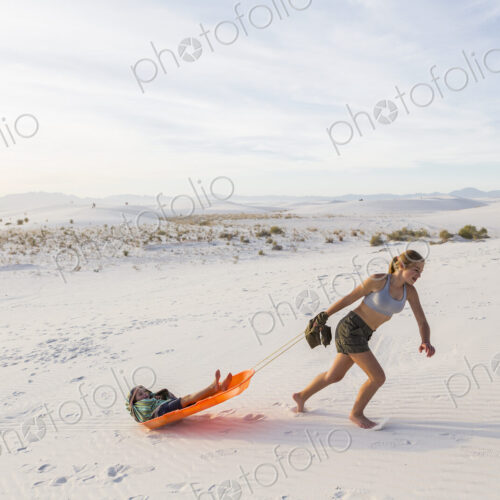 13 year old girl pulling her brother in sled at sunset, White Sands Nat'l Monument, NM 13 year old girl pulling her brother in sled at sunset, White Sands Nat'l Monument, NM