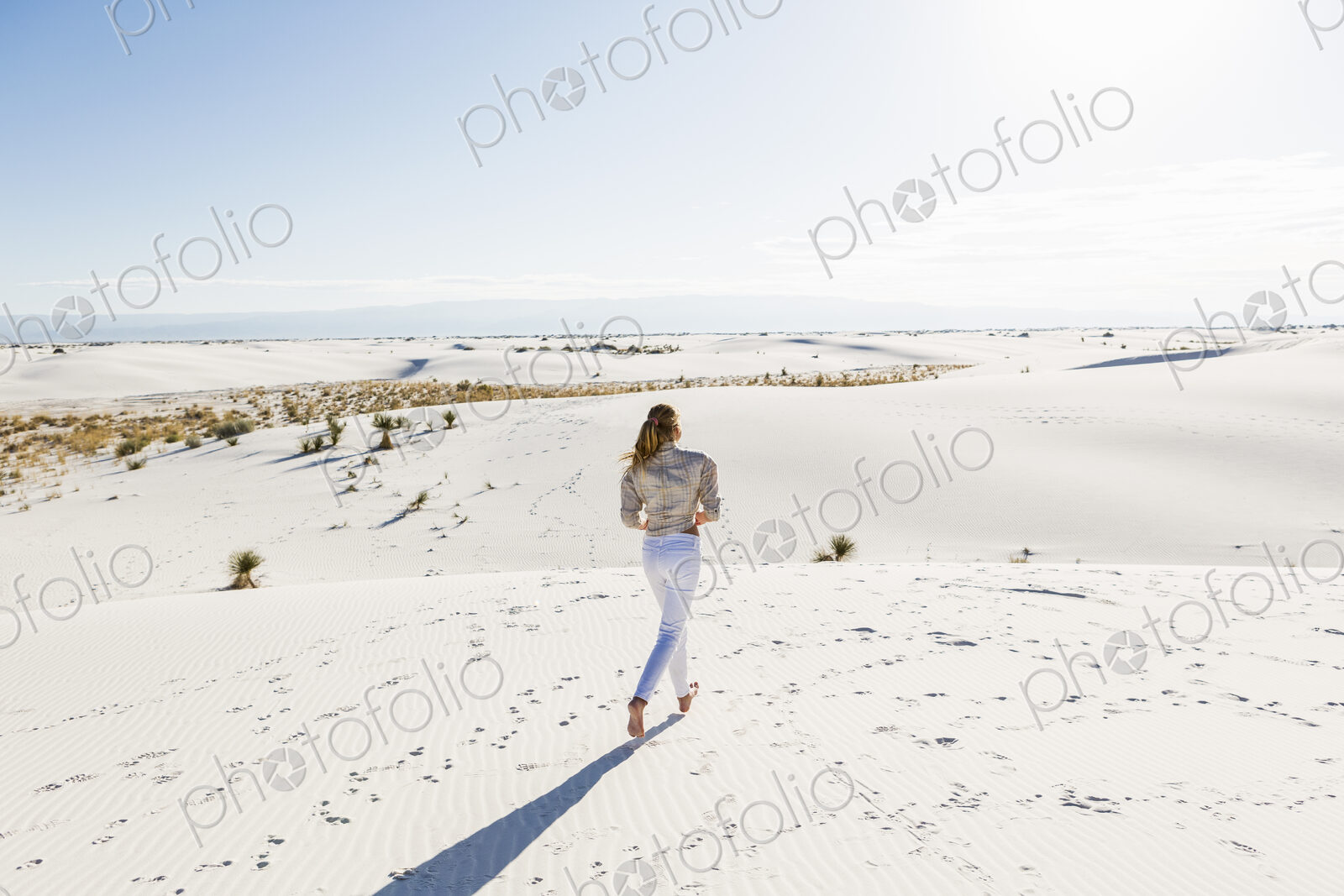 13 year old girl standing looking at a vast open space of sand dunes.