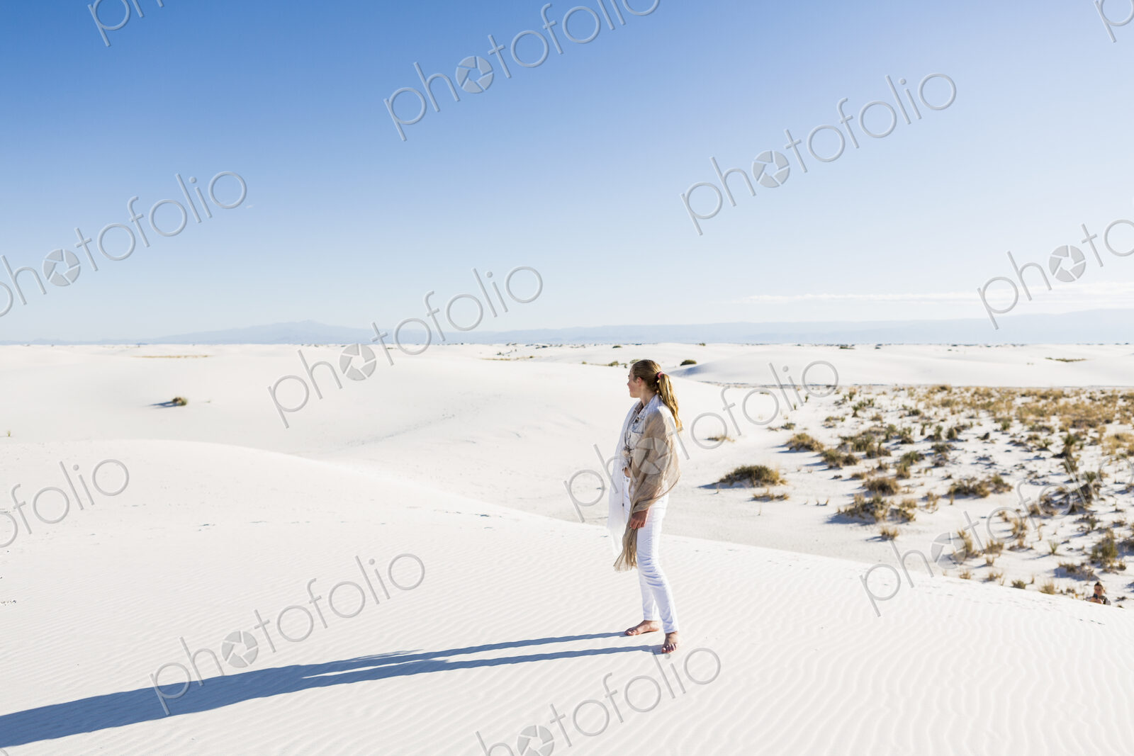 13 year old girl standing looking at a vast open space of sand dunes.