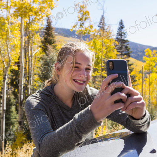 13 year old girl taking pictures with her smart phone, looking at autumn aspen trees 13 year old girl taking pictures with her smart phone, looking at autumn aspen trees