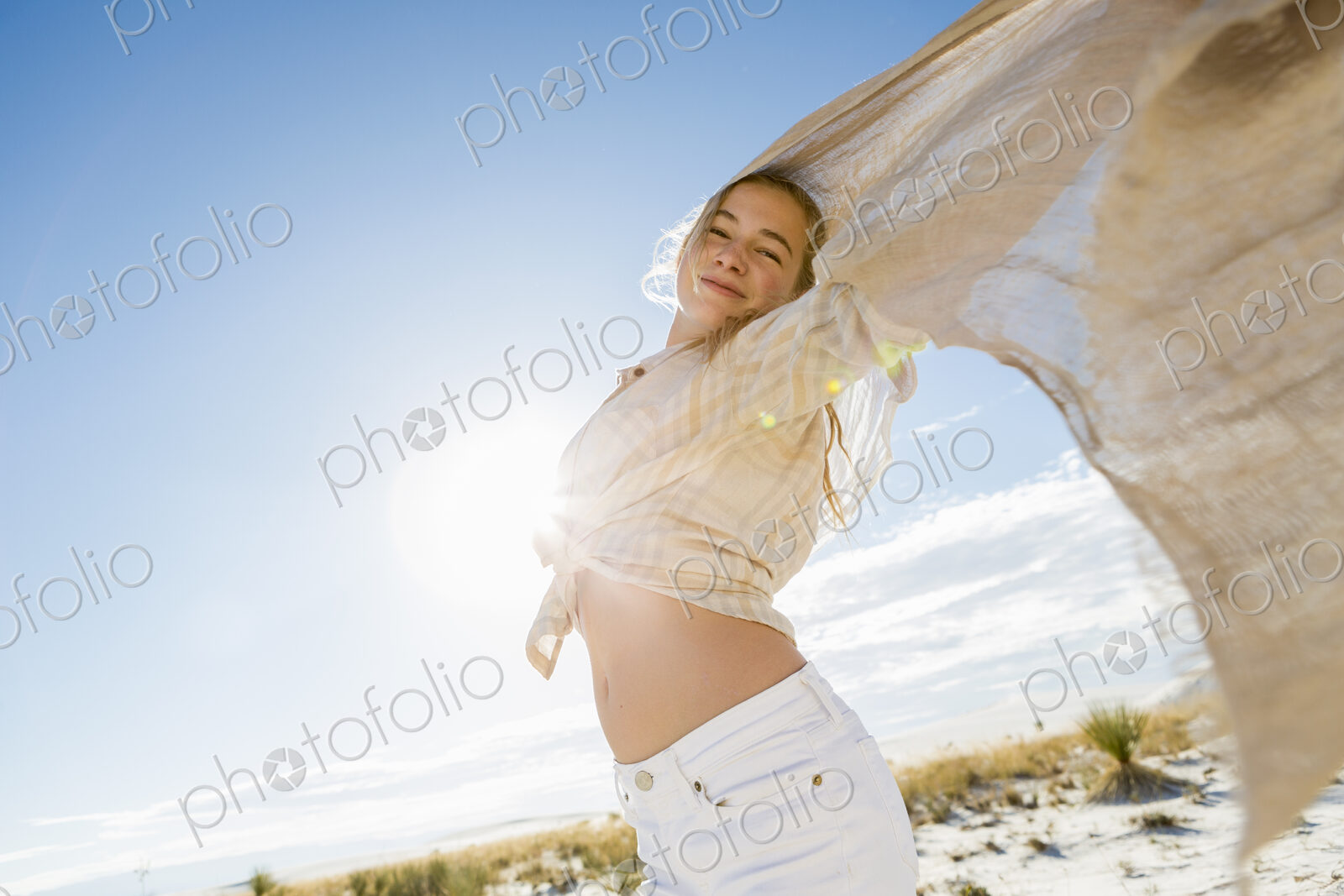 13 year old girl with arms raised holding a light shawl dancing in open space.
