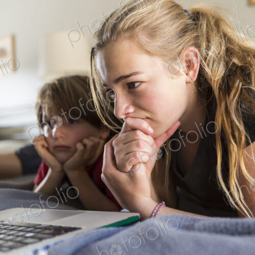 13 year old sister and her brother looking at laptop on bed 13 year old sister and her brother looking at laptop on bed