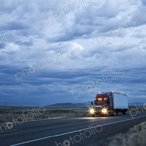 3/4 front view of a commercial truck on the road in the early evening in eastern… 3/4 front view of a commercial truck on the road in the early evening in eastern…