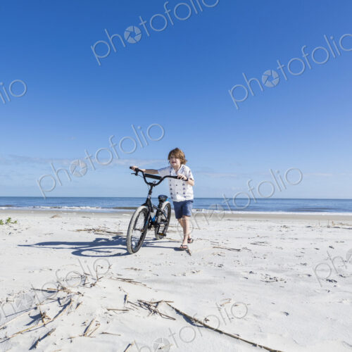 6 year old boy biking on beach, St. Simon's Island, Georgia
