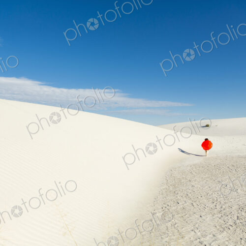 6 year old boy carrying an orange sled in a white undulating dune landscape. 6 year old boy carrying an orange sled in a white undulating dune landscape.
