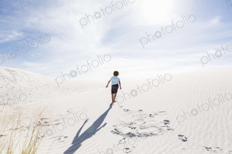 6 year old boy climbing sand dune