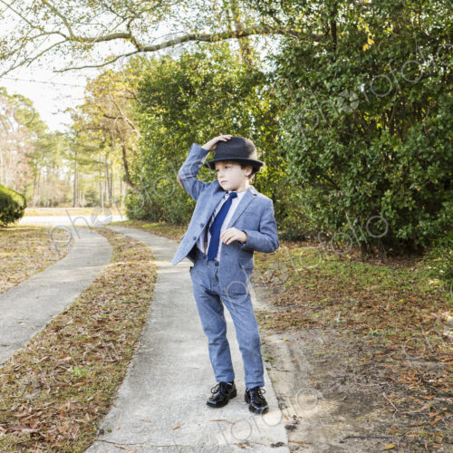 6 year old boy dressed in suit and wearing fedora, in driveway 6 year old boy dressed in suit and wearing fedora, in driveway