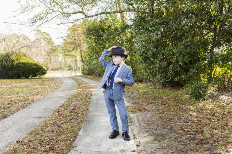 6 year old boy dressed in suit and wearing fedora, in driveway