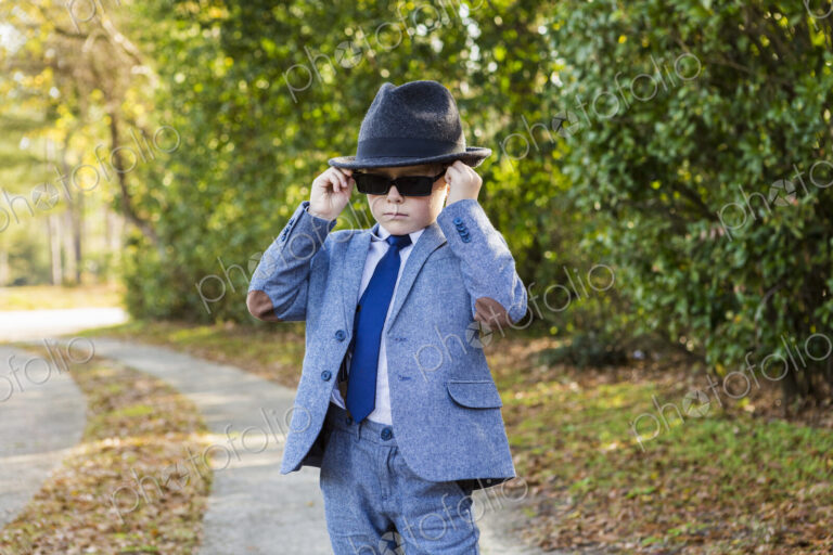 6 year old boy dressed in suit and wearing fedora, in driveway