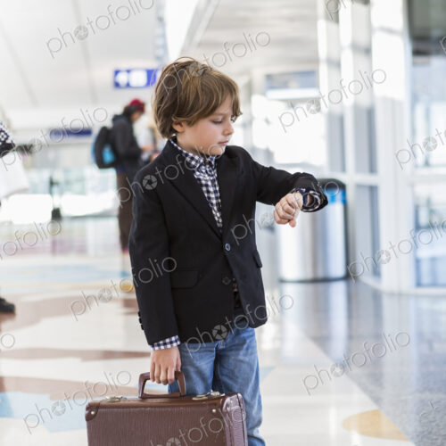 6 year old boy looking at his watch in airport 6 year old boy looking at his watch in airport