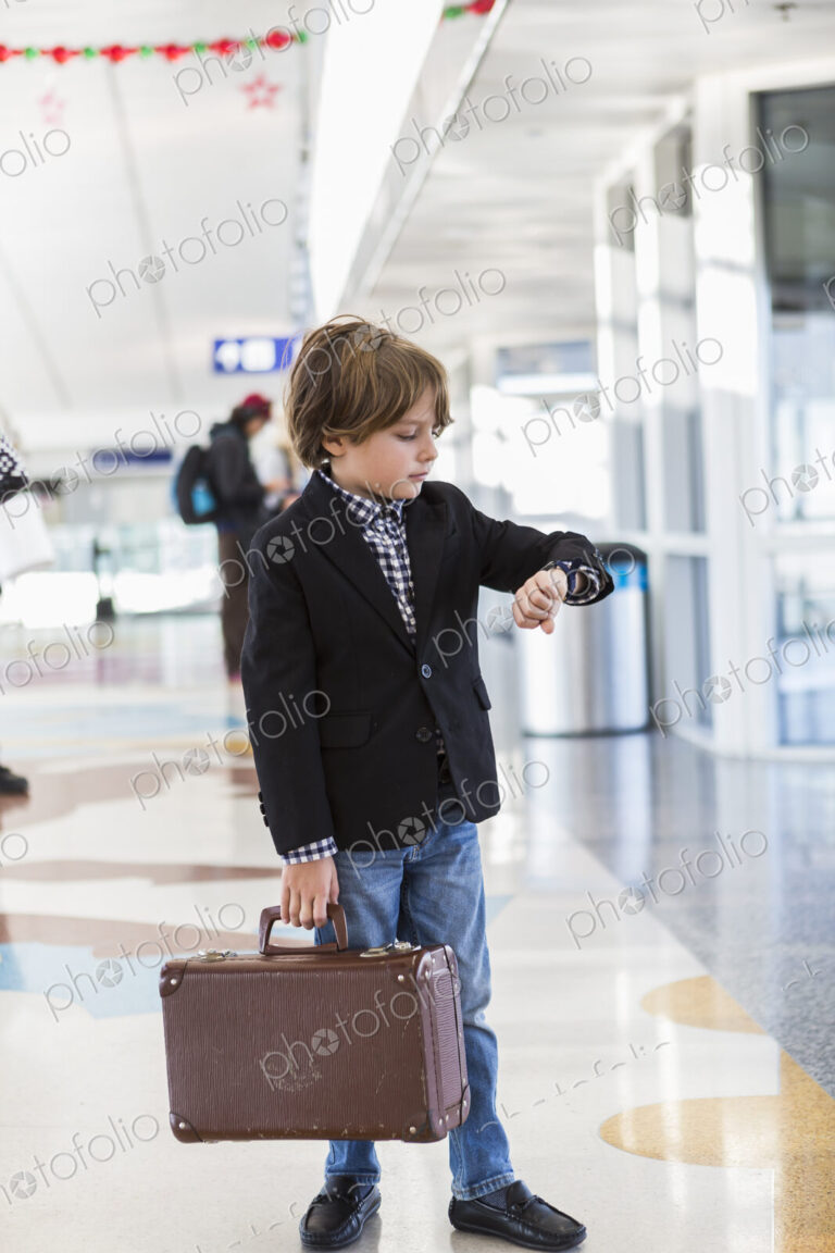 6 year old boy looking at his watch in airport