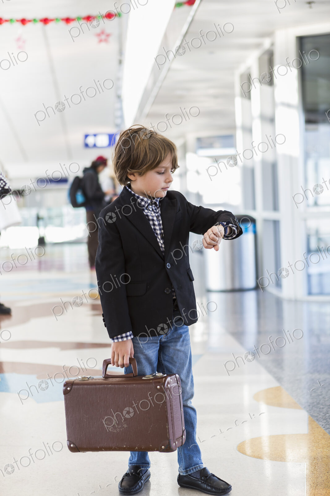 6 year old boy looking at his watch in airport