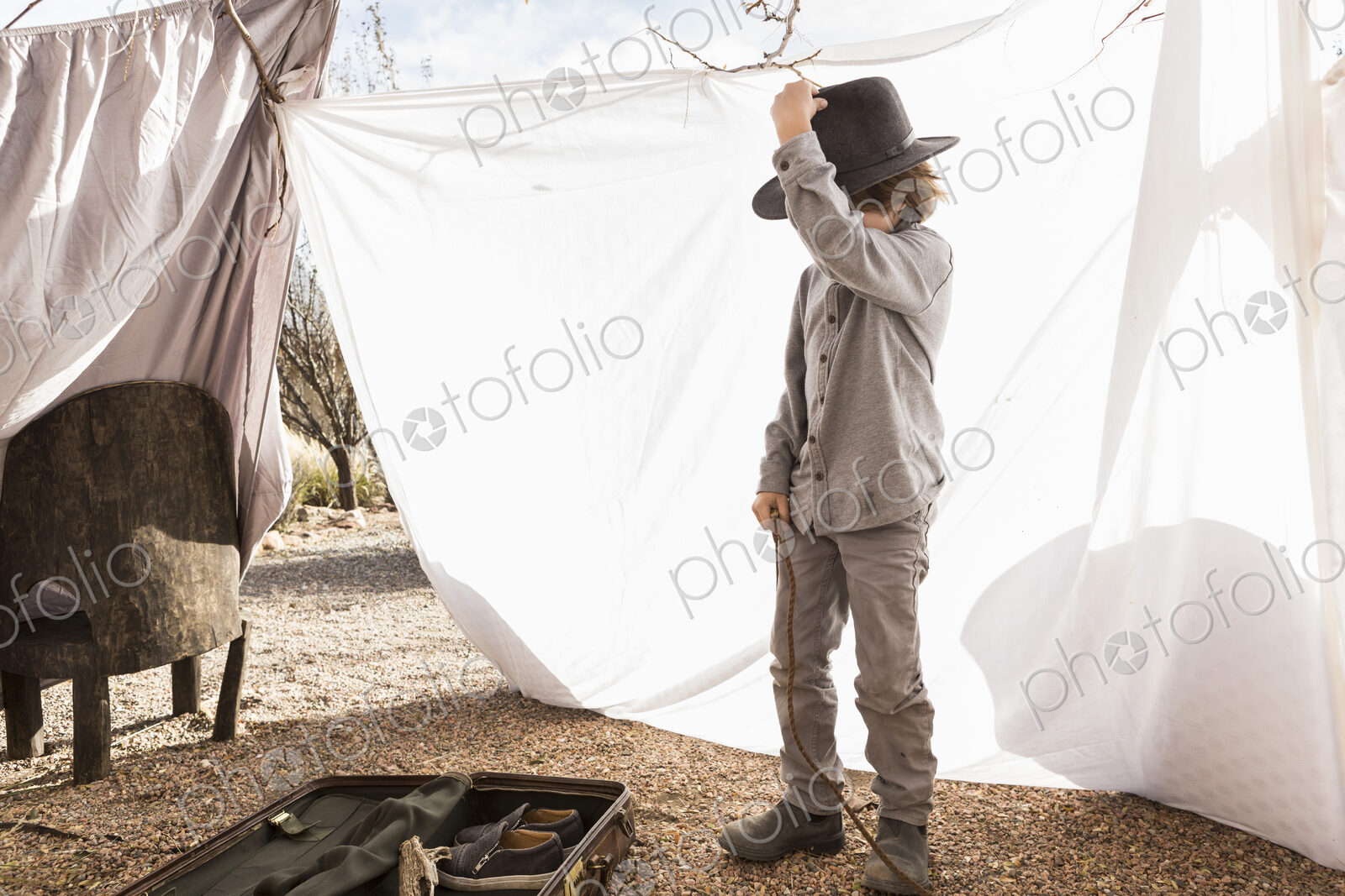 6 year old boy playing in an outdoor tent made of sheets
