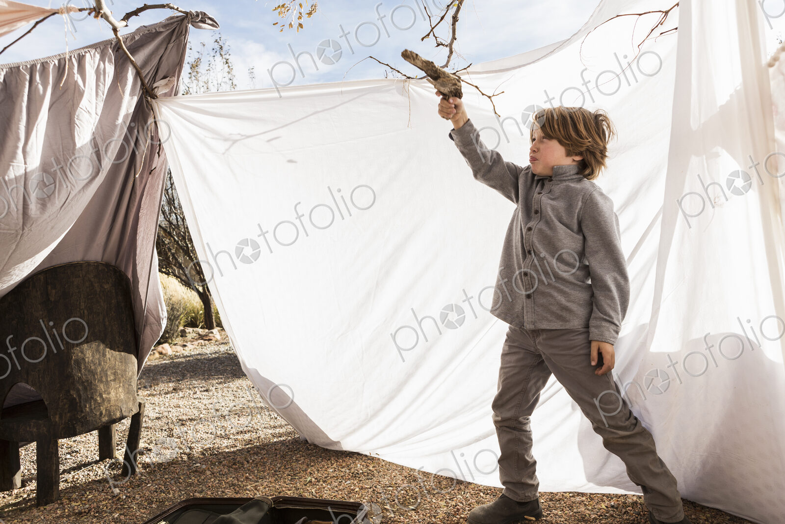 6 year old boy playing in an outdoor tent made of sheets