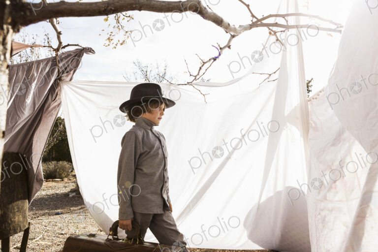 6 year old boy playing in an outdoor tent made of sheets