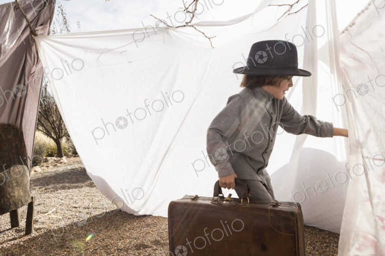 6 year old boy playing in an outdoor tent made of sheets