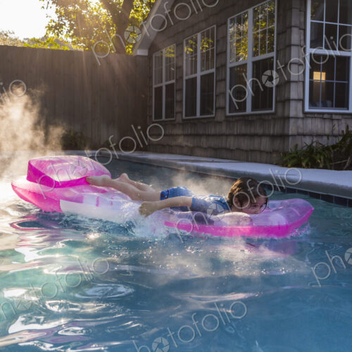 6 year old boy playing in pool at sunrise 6 year old boy playing in pool at sunrise