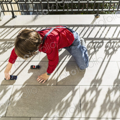 6 year old boy playing with toy cars on terrace 6 year old boy playing with toy cars on terrace