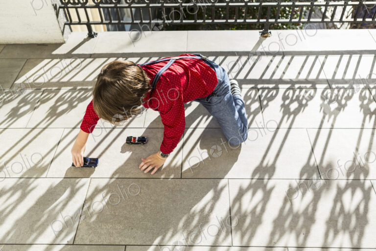 6 year old boy playing with toy cars on terrace