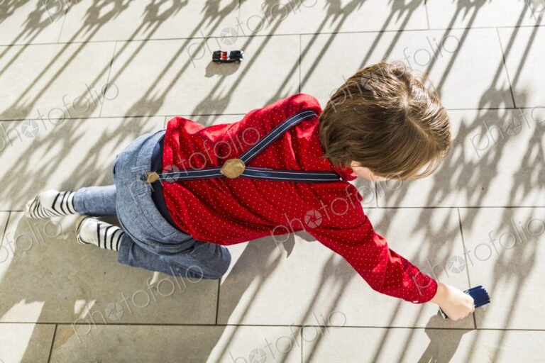 6 year old boy playing with toy cars on terrace