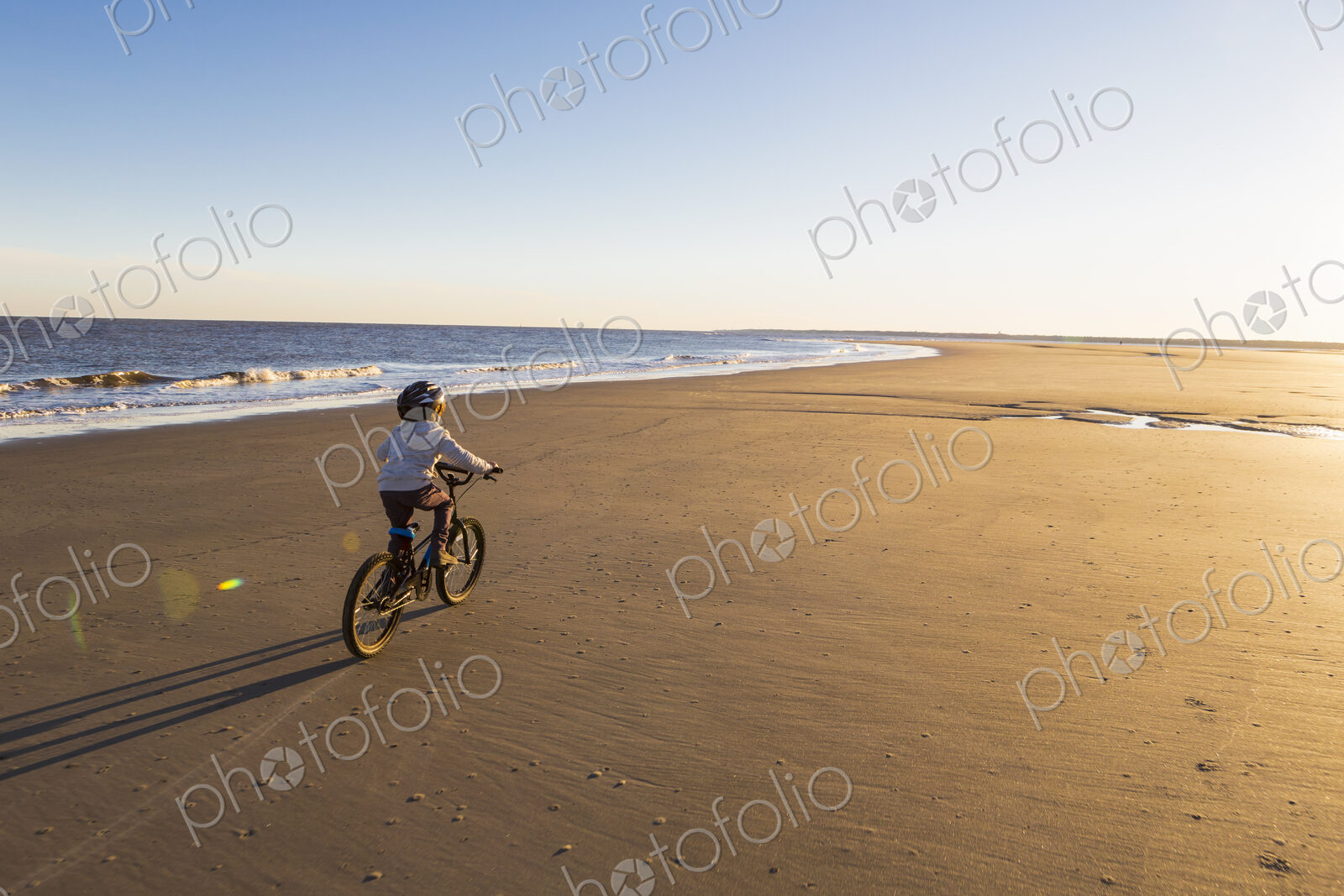 6 year old boy riding a bicycle on a beach