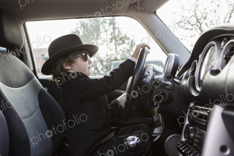 6 year old boy sitting in car holding steering wheel