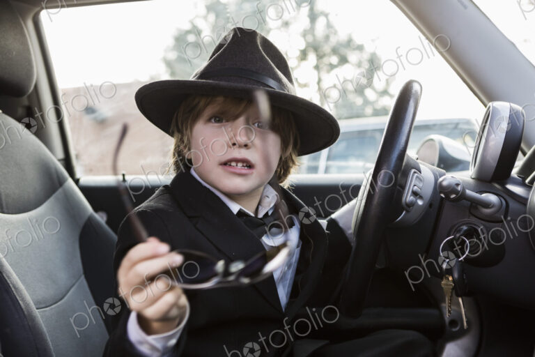 6 year old boy sitting in car holding steering wheel