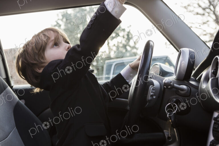 6 year old boy sitting in car holding steering wheel