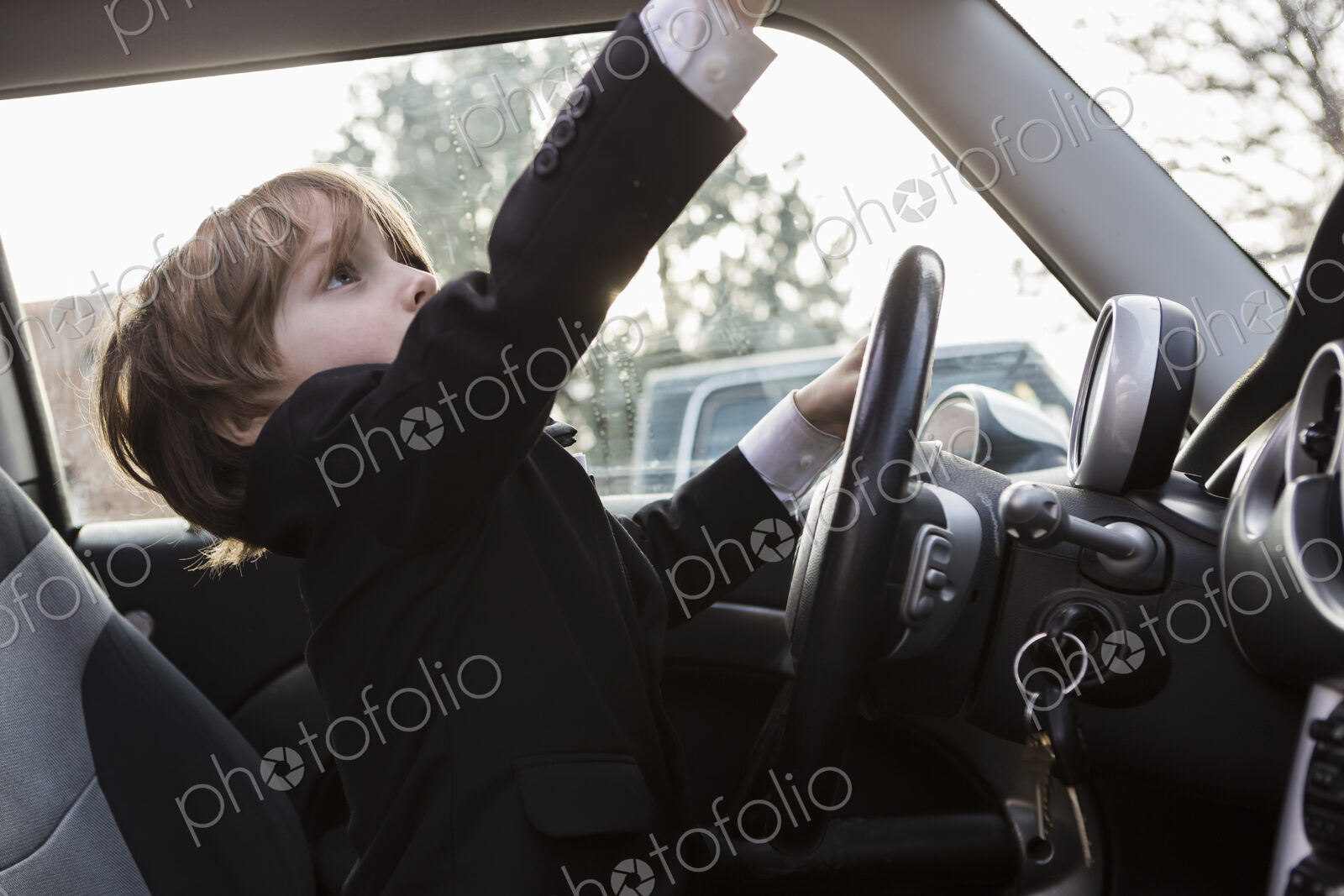 6 year old boy sitting in car holding steering wheel