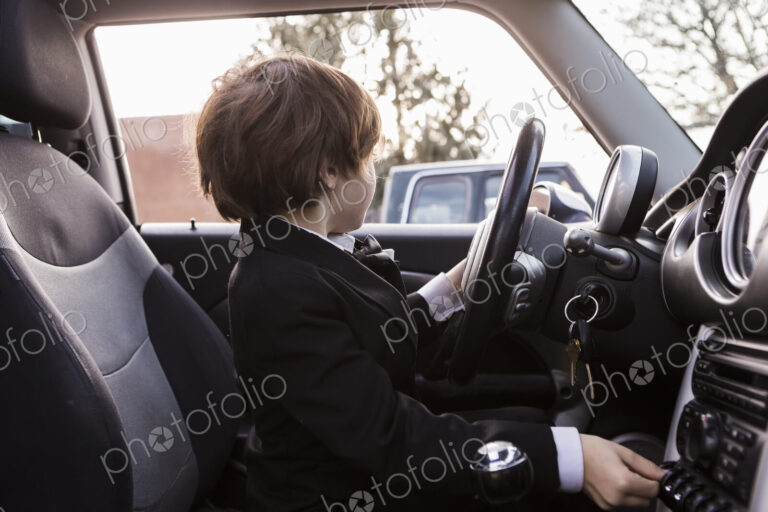 6 year old boy sitting in car holding steering wheel