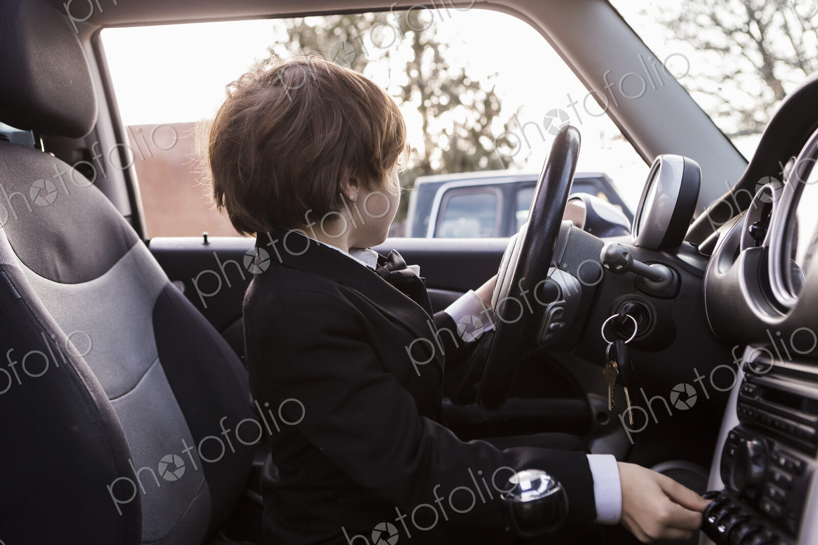 6 year old boy sitting in car holding steering wheel