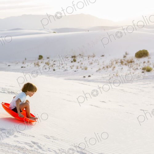 6 year old boy sledding down dunes, White Sands Nat'l Monument, NM 6 year old boy sledding down dunes, White Sands Nat'l Monument, NM