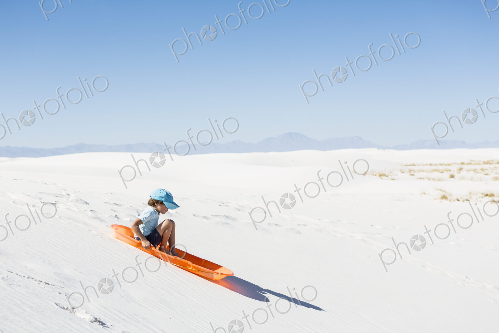 6 year old boy sledding on sand dune