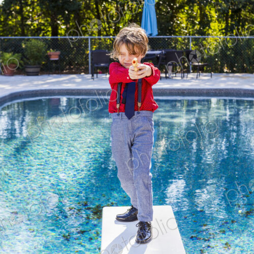 6 year old boy standing on diving board overlooking pool 6 year old boy standing on diving board overlooking pool