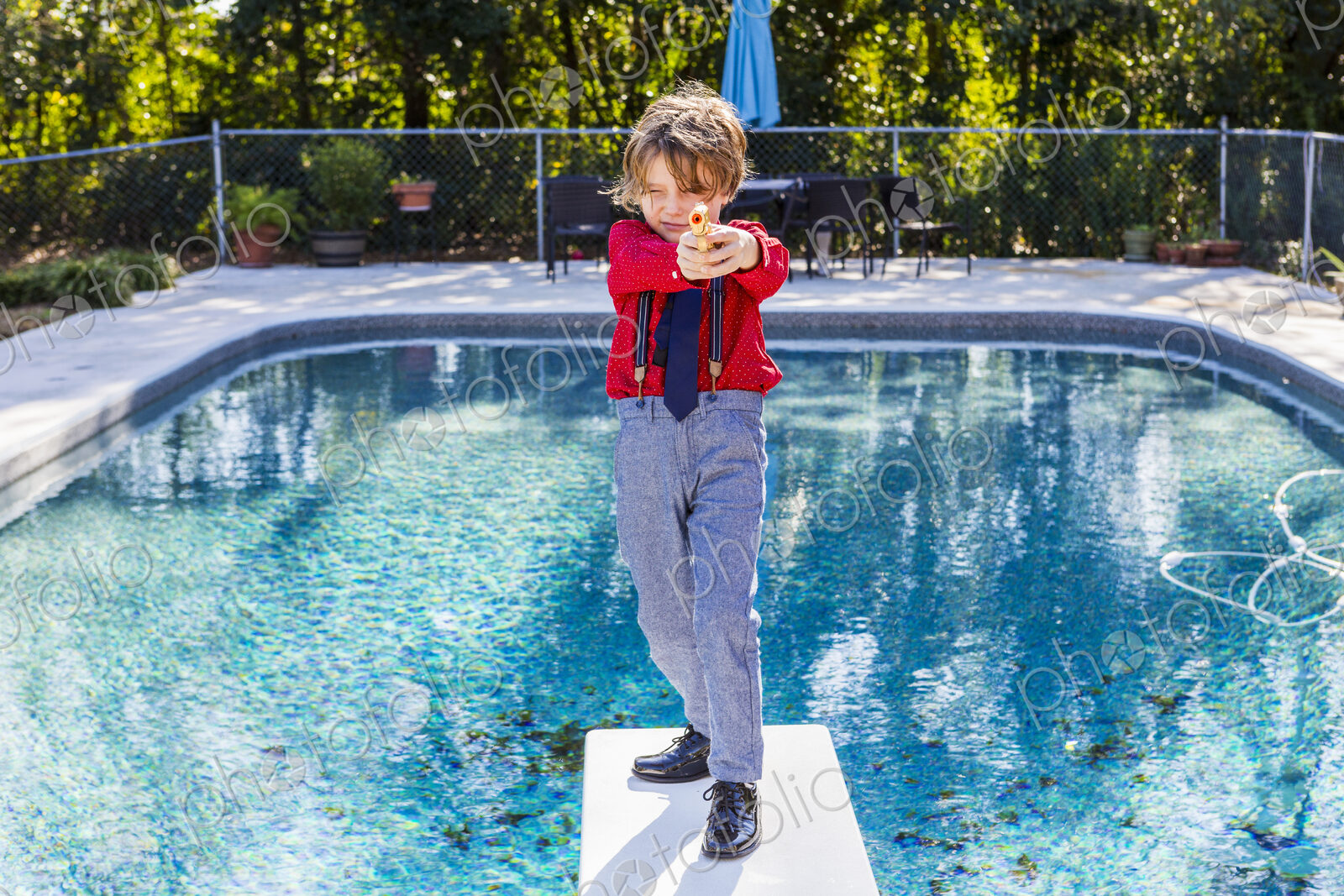 6 year old boy standing on diving board overlooking pool