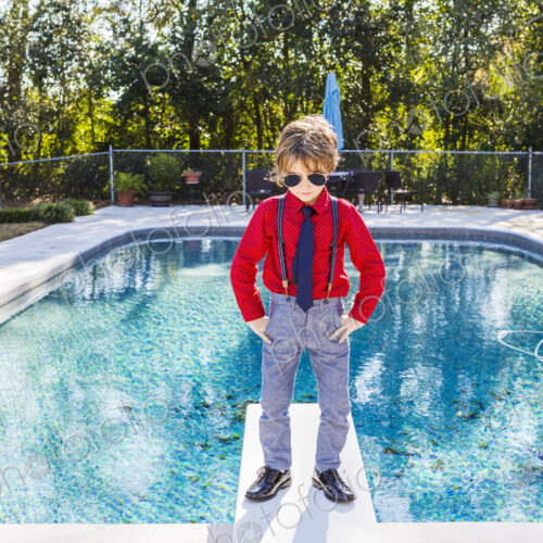 6 year old boy standing on diving board overlooking pool 6 year old boy standing on diving board overlooking pool