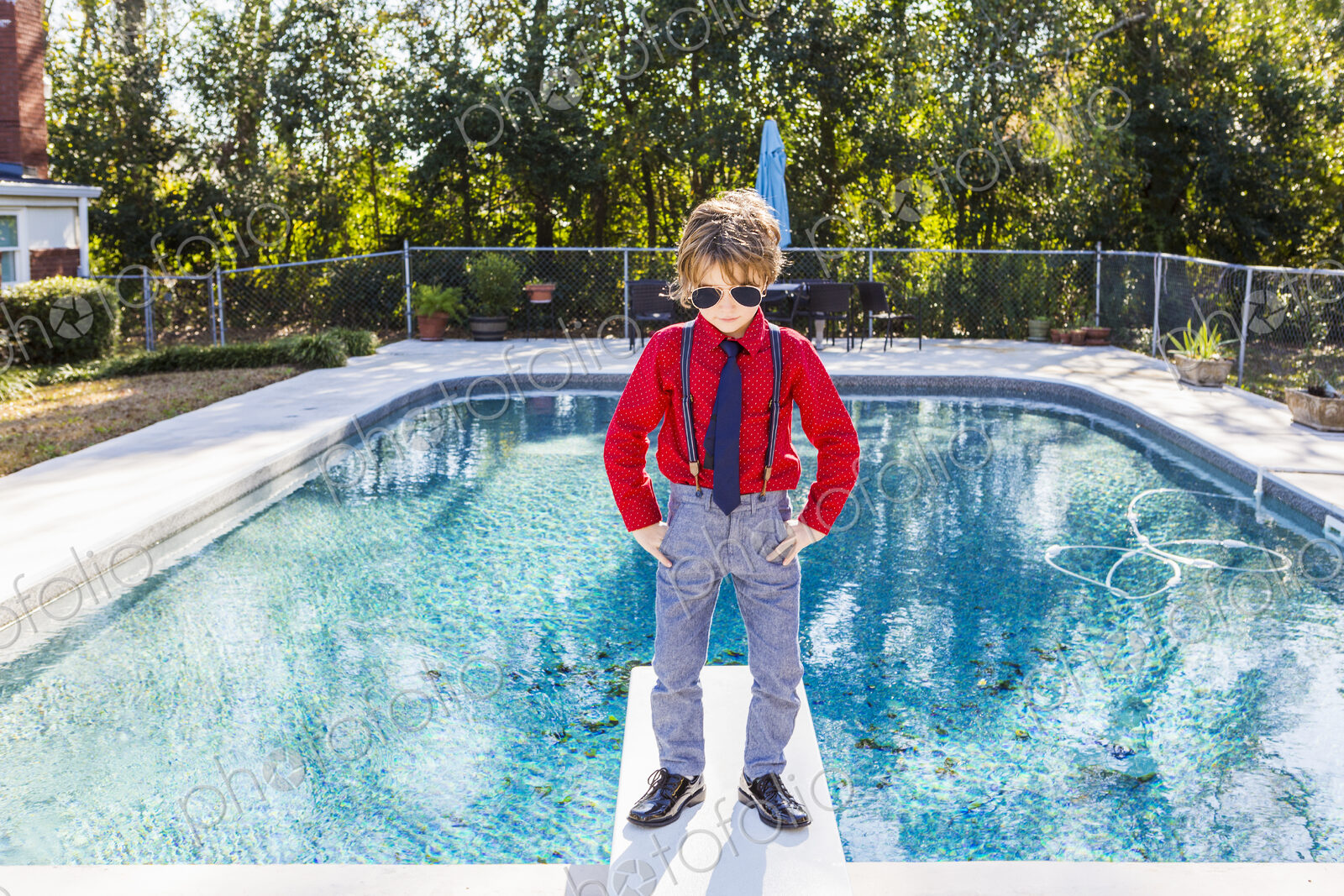 6 year old boy standing on diving board overlooking pool