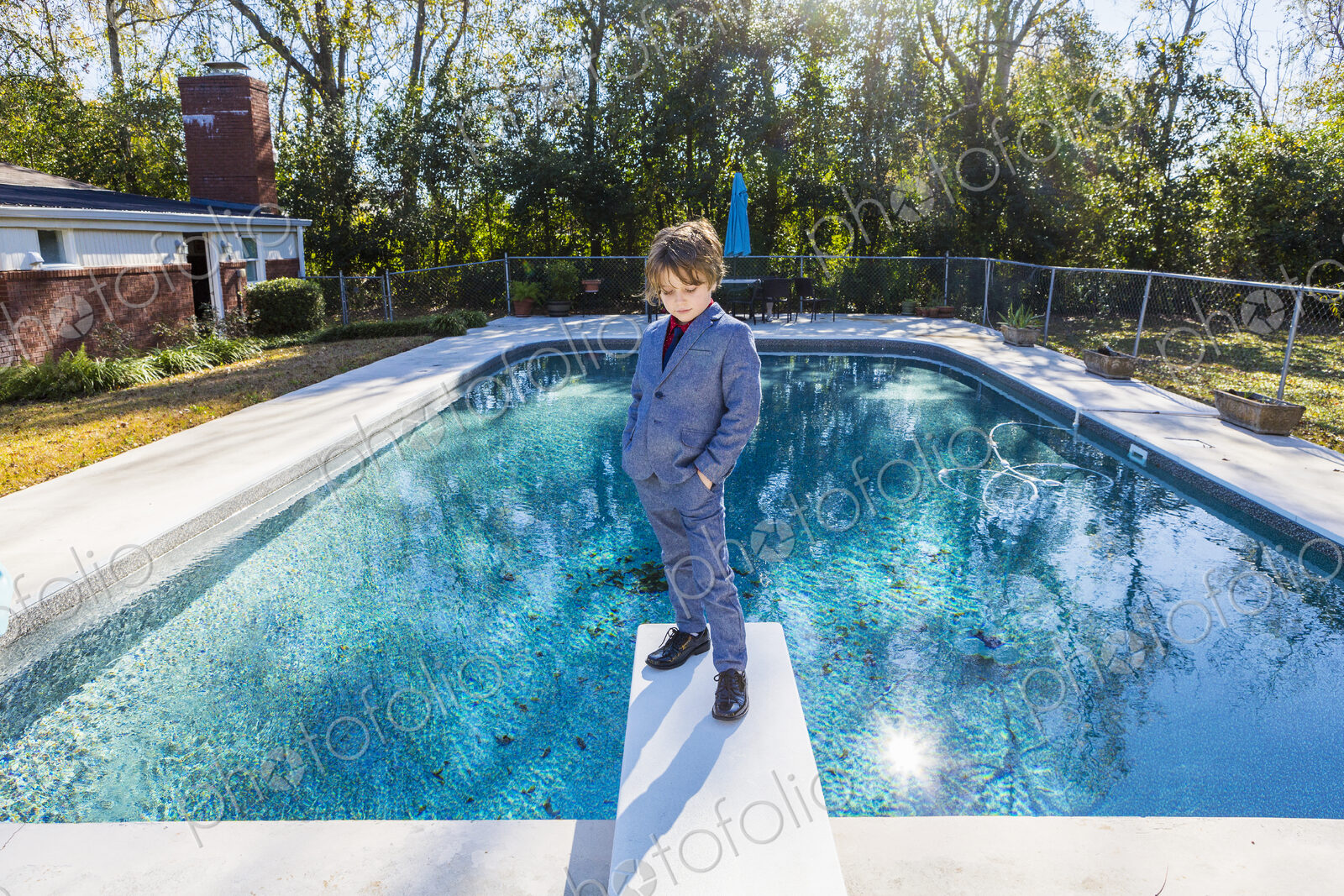 6 year old boy standing on diving board overlooking pool