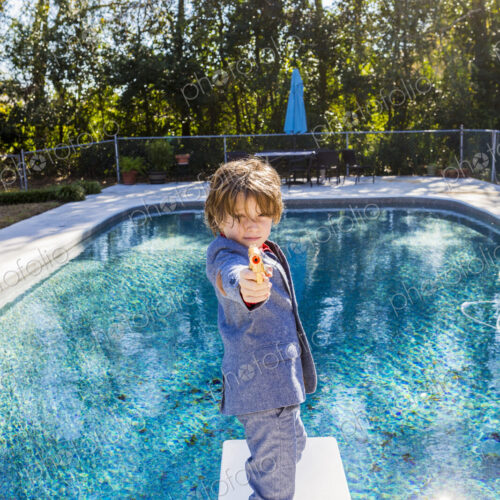 6 year old boy standing on diving board overlooking pool 6 year old boy standing on diving board overlooking pool