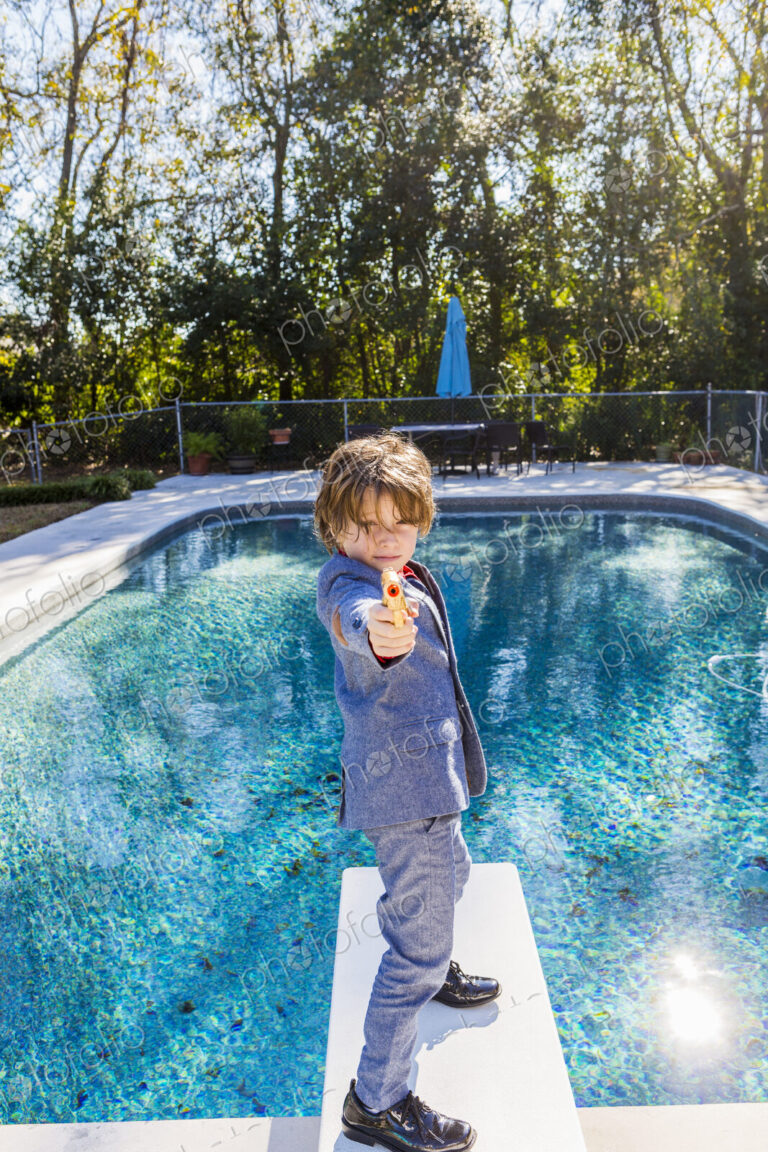 6 year old boy standing on diving board overlooking pool
