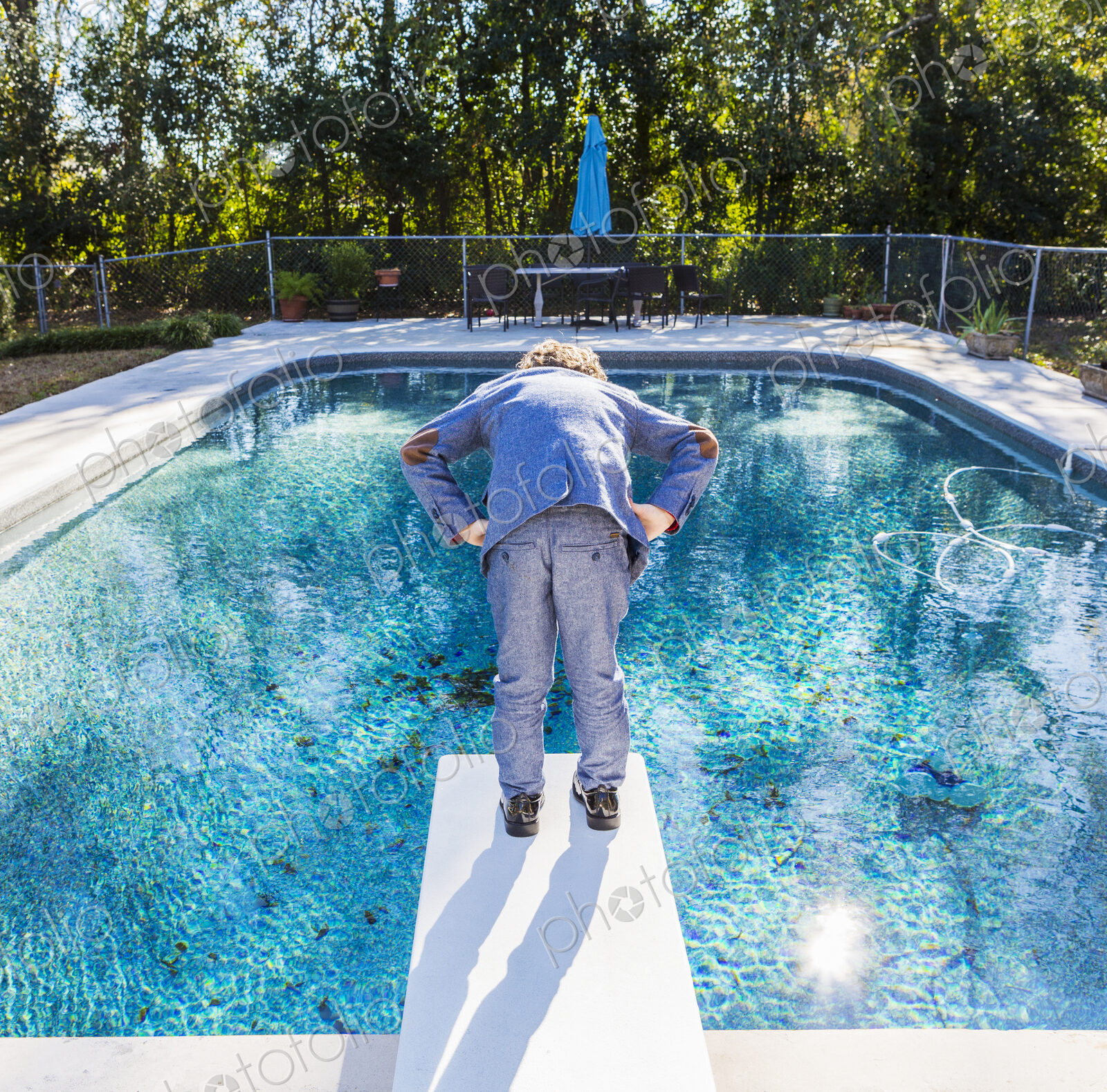6 year old boy standing on diving board overlooking pool
