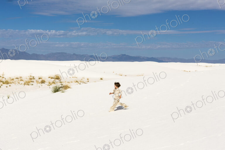 6 year old boy walking in white sand dunes.