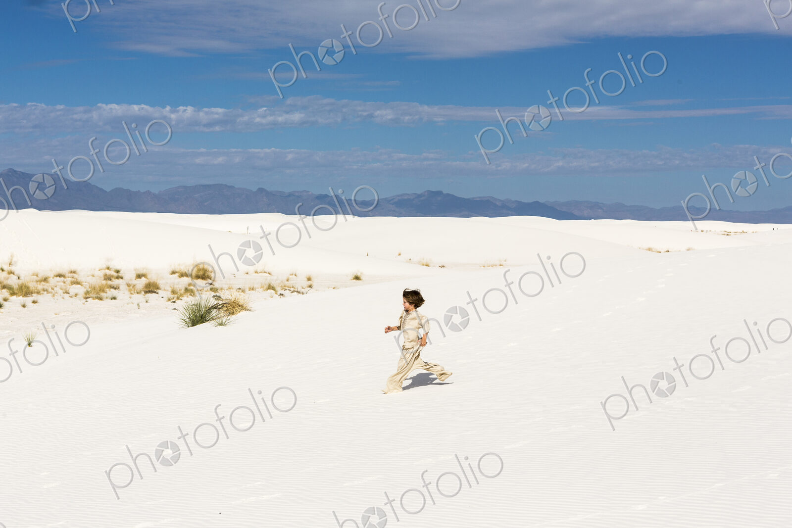 6 year old boy walking in white sand dunes.